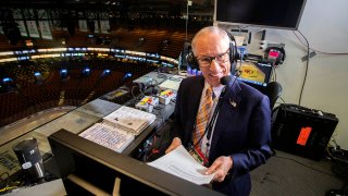 In this May 27, 2019, file photo, hours before Game 1 of the Stanley Cup Finals between the Boston Bruins and the St. Louis Blues at TD Garden in Boston, NBC hockey play-by-play announcer Mike Emrick does voice overs in the empty arena.