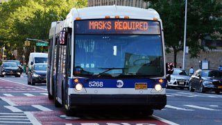 An MTA bus displays a 'MASKS REQUIRED' sign in New York City