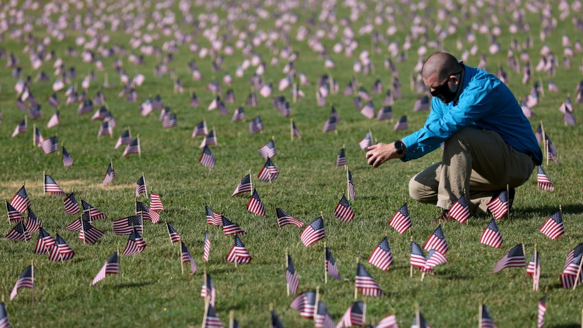 WASHINGTON, DC - SEPTEMBER 22: Chris Duncan, whose 75 year old mother Constance died from COVID on her birthday, photographs a COVID Memorial Project installation of 20,000 American flags on the National Mall as the United States crosses the 200,000 lives lost in the COVID-19 pandemic September 22, 2020 in Washington, DC. The flags are displayed on the grounds of the Washington Monument facing the White House.