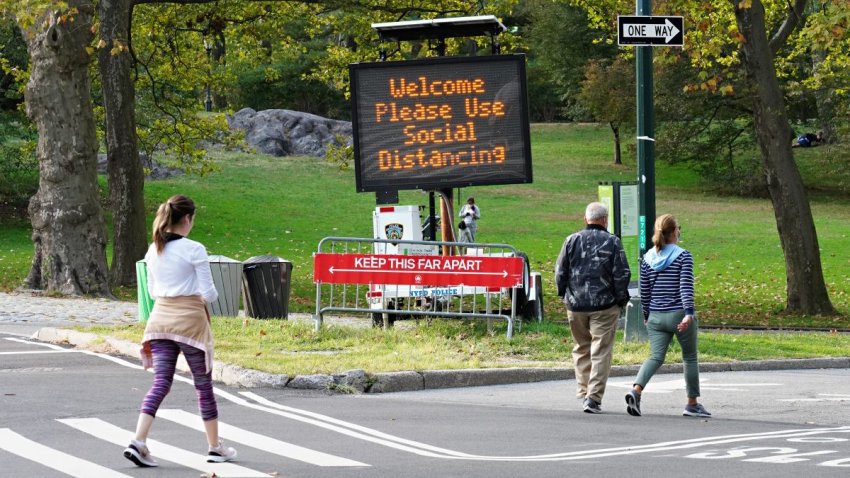 People walk by social distancing signage in Central Park as the city continues the re-opening efforts following restrictions imposed to slow the spread of coronavirus on October 19, 2020 in New York City.