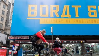 People ride bicycles by a billboard for Borat Subsequent Moviefilm in Times Square as the city continues the re-opening efforts following restrictions imposed to slow the spread of coronavirus on October 28, 2020 in New York City.