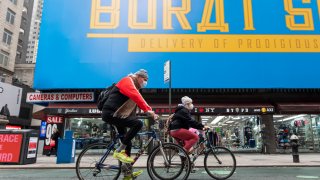 People ride bicycles by a billboard for Borat Subsequent Moviefilm in Times Square as the city continues the re-opening efforts following restrictions imposed to slow the spread of coronavirus on October 28, 2020 in New York City.