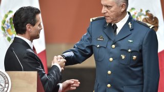 Mexican President Enrique Pena Nieto (L) congratulates Defense Secretary Gral. Salvador Cienfuegos Zepeda after his speech about recaptured drug baron Joaquin Guzman Loera, AKA "El Chapo", in Mexico City on January 8, 2016. Mexican marines recaptured fugitive drug kingpin Joaquin "El Chapo" Guzman on Friday in the northwest of the country, six months after his spectacular prison break embarrassed authorities.