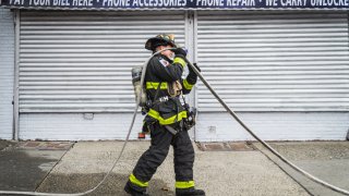 A firefighter is fixing a fire hose during the fire scene