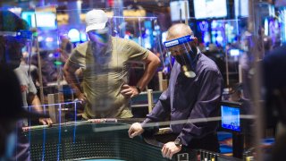 An employee wears a protective mask and face shield while overseeing the craps table at the Ocean Casino Resort during the Covid-19 pandemic in Atlantic City, New Jersey, U.S., on Thursday, July 2, 2020.