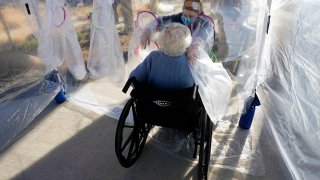 Lara Angevine (R) reaches to hug her mother Barbara through the wall of a plastic "hug tent" outside the Accel at Longmont skilled nursing facility on December 4, 2020 in Longmont, Colorado. The hug tent, built by TRU Community Care, allowed people from the outside to physically touch residents at the facility for the first time since the COVID-19 pandemic hit.