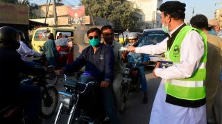 A Arsalan Helpline Welfare Trust (AHWT) worker distributes face masks to motorists along a street as a preventive measure against the spread of the Covid-19 coronavirus, in Karachi on December 14, 2020.