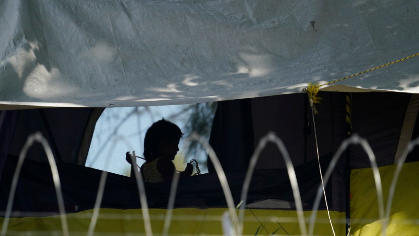 FILE - In this Nov. 18, 2020, file photo, a young girl plays in her family's tent at a camp of asylum seekers stuck at America's doorstep, in Matamoros, Mexico. Increasing numbers of parents and children are crossing the border, driven by violence and poverty in Central America and growing desperation in migrant camps in Mexico. U.S. Customs and Border Protection said Monday, Dec. 14, 2020 that it made 4,592 apprehensions of unaccompanied immigrant children in November, more than six times the figure in April.