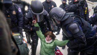FILE- A woman, later identified as Sharon Pineo, is helped up by police during a violent riot, Wednesday, Jan. 6, 2021, at the Capitol in Washington. Pineo, a member of Malta, N.Y. a New York town’s zoning board has resigned, Monday, Jan. 11, after she was seen in photos taken at the U.S. Capitol on the day it was stormed.