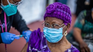 Registered Nurse Ebony Thomas (L) administers a Moderna Covid-19 vaccine to Cecilia Onwytalu, 89, at Kedren Community Health Center, in South Central Los Angeles, California on February 16, 2021.