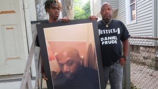 FILE - In this Sept. 3, 2020, file photo, Joe Prude, brother of Daniel Prude, right, and his son Armin, stand with a picture of Daniel Prude in Rochester, N.Y. Daniel Prude, 41, suffocated after police in Rochester put a "spit hood" over his head while he was being taken into custody. He died March 30, after he was taken off life support, seven days after the encounter with police. The independent investigator leading a probe of the city's handling of Prude's death says the ex-police chief is refusing to cooperate.