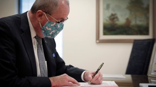 This photo provided by the New Jersey Governor's Office shows Gov. Phil Murphy as he signs into law legislation to set up a recreational marijuana marketplace, Monday, Feb. 22, 2021, in Trenton, N.J. A recreational marijuana marketplace, cannabis decriminalization and looser penalties for underage possession of the drug and alcohol became law in New Jersey, more than three months after voters overwhelmingly approved a ballot question to legalize adult use of the drug.