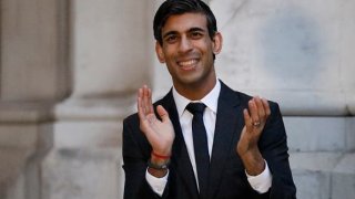 Britain’s Chancellor of the Exchequer Rishi Sunak takes part in a national “clap for carers” to show thanks for the work of Britain’s National Health Service (NHS) workers and frontline medical staff around the country as they battle with the coronavirus pandemic, on the steps of the Foreign and Commonwealth Office (FCO) on April 16, 2020 in London.
