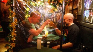 Brendan Byrnes and Stephen Cabral clink their drinks at Julius' in New York on March 19, 2021. Byrnes and Cabral got married at Julius' in 2015