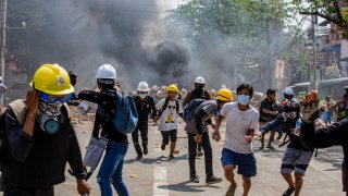 Anti military coup protesters run after military soldiers start shooting at them during a demonstration against the military coup.