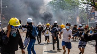 Anti military coup protesters run after military soldiers start shooting at them during a demonstration against the military coup.