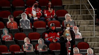 Fans sit among the cut outs as they watch warm ups between the New Jersey Devils and the New York Islanders at Prudential Center