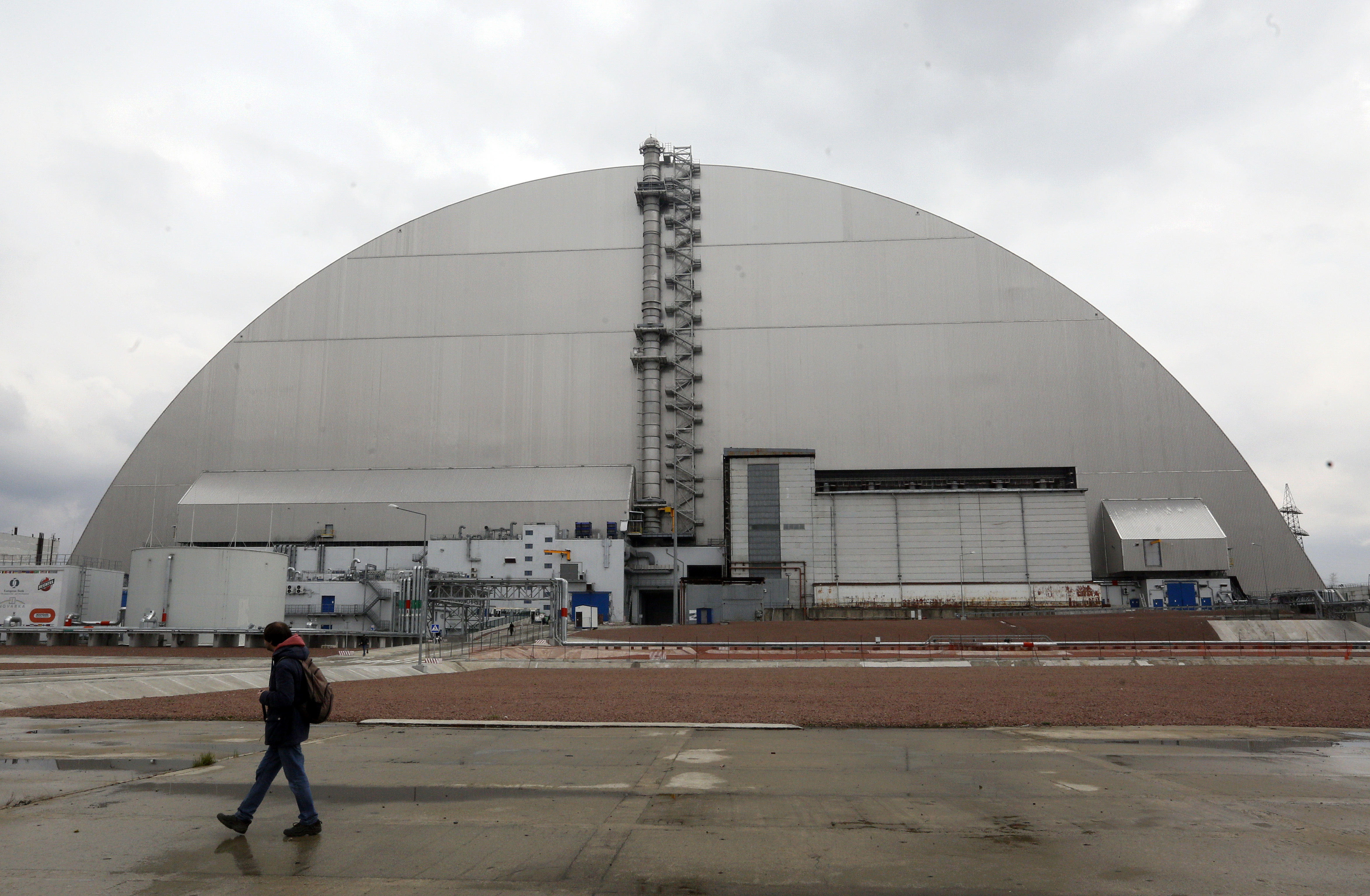 A man walks past a shelter covering the exploded reactor at the Chernobyl nuclear plant, in Chernobyl, Ukraine, April 15, 2021.