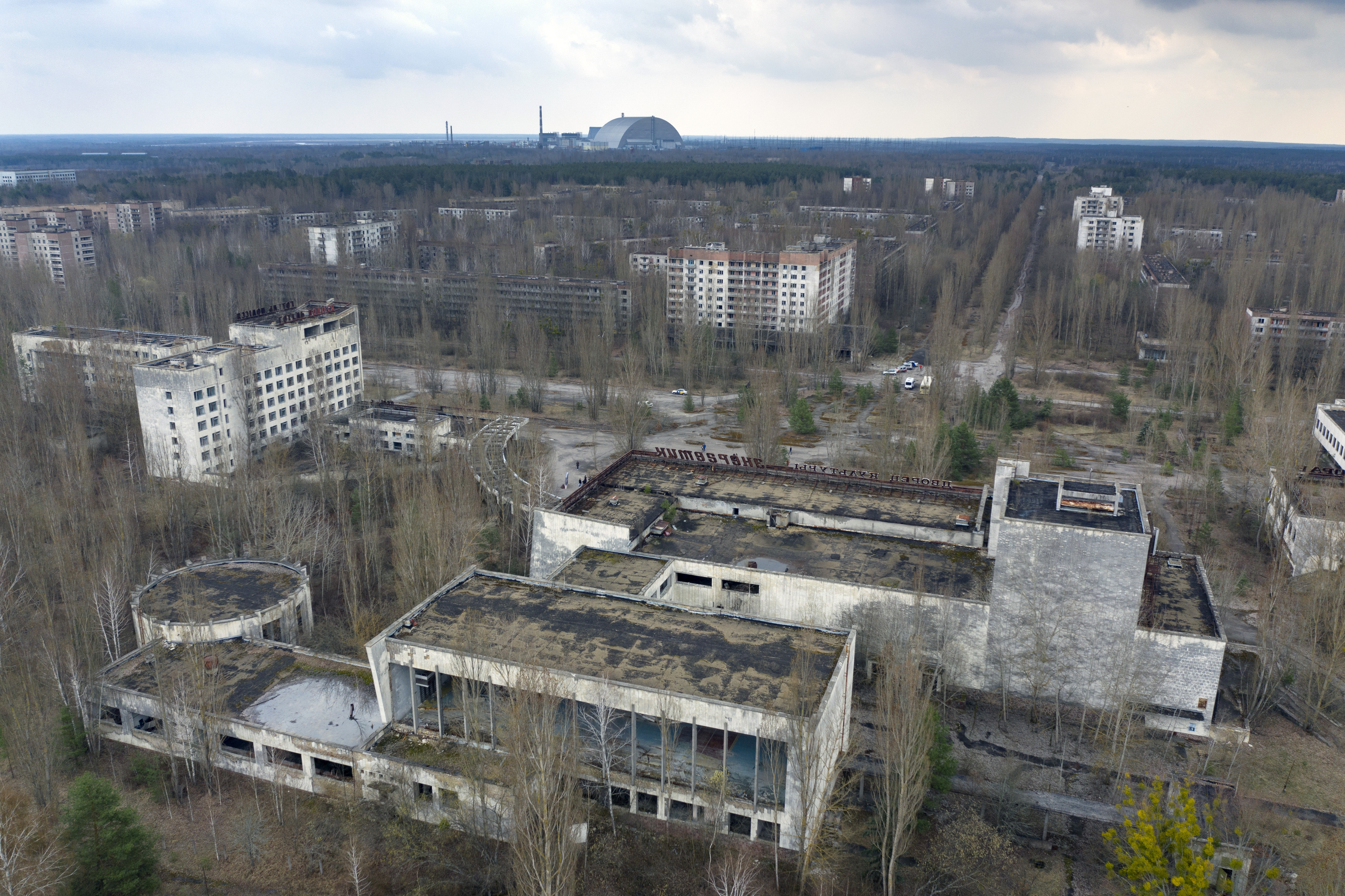 A view of the ghost town of Pripyat with a shelter covering the exploded reactor at the Chernobyl nuclear plant in the background, Ukraine, April 15, 2021. The vast and empty Chernobyl Exclusion Zone around the site of the world’s worst nuclear accident is a baleful monument to human mistakes. Yet 35 years after a power plant reactor exploded, Ukrainians also look to it for inspiration, solace and income.