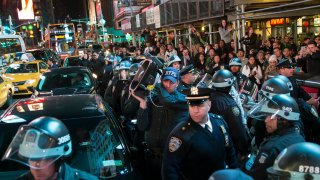 A police officer holds a Long Range Acoustic Device (LRAD), or sound cannon, as they block protestors on a march through Times Square