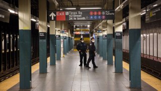 New York Police Department (NYPD) officers wearing protective masks patrol a Times Square subway platform in New York