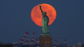 Pink supermoon behind Statue of Liberty