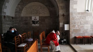 In this March 28, 2021, file photo, priests pause on Palm Sunday on the Mount of Olives in Jerusalem. A year after coronavirus restrictions halted mass gatherings, Christians are celebrating Holy Week together.