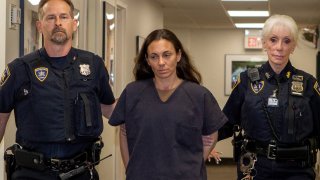 In this June 12, 2019 photo, former NYPD police officer Valerie Cincinelli, center, is escorted for an appearance in Nassau County Matrimonial Court in Mineola