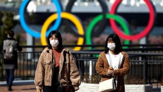 People wearing protective face masks, following an outbreak of the coronavirus, are seen in front of the Giant Olympic rings at the waterfront area at Odaiba Marine Park in Tokyo, Japan, February 27, 2020.