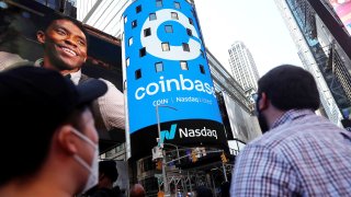 People watch as the logo for Coinbase Global Inc, the biggest U.S. cryptocurrency exchange, is displayed on the Nasdaq MarketSite jumbotron at Times Square in New York, U.S., April 14, 2021.