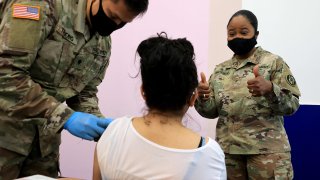 Maryland National Guard Brigadier General Janeen Birckhead visits with a woman as she receives her Moderna coronavirus vaccine from Specialist James Truong (L) at CASA de Maryland’s Wheaton Welcome Center on May 21, 2021 in Wheaton, Maryland.