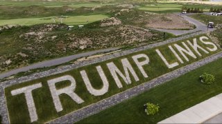 Patrons play the links as a giant branding sign is displayed with flagstones at Trump Golf Links at Ferry Point in the Bronx borough of New York on Tuesday, May 4, 2021. (AP Photo/John Minchillo)