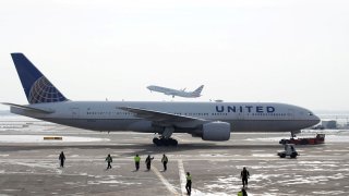 A United Airlines Boeing 777-200ER plane is towed as an American Airlines Boeing 737 plane departs from O’Hare International Airport in Chicago, Illinois.