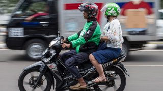 A passenger takes a ride on a Gojek motorcycle taxi in Jakarta on May 24, 2018.