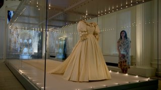 A staff member poses for photographers next to the wedding dress of Britain's Princess Diana during a media preview for the "Royal Style in the Making" exhibition at Kensington Palace in London