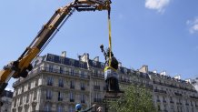 Workers secure the move of the "Liberty Enlightening the World" by Frederic Auguste Bartholdi, a mini-replica of the French-designed Statue of Liberty