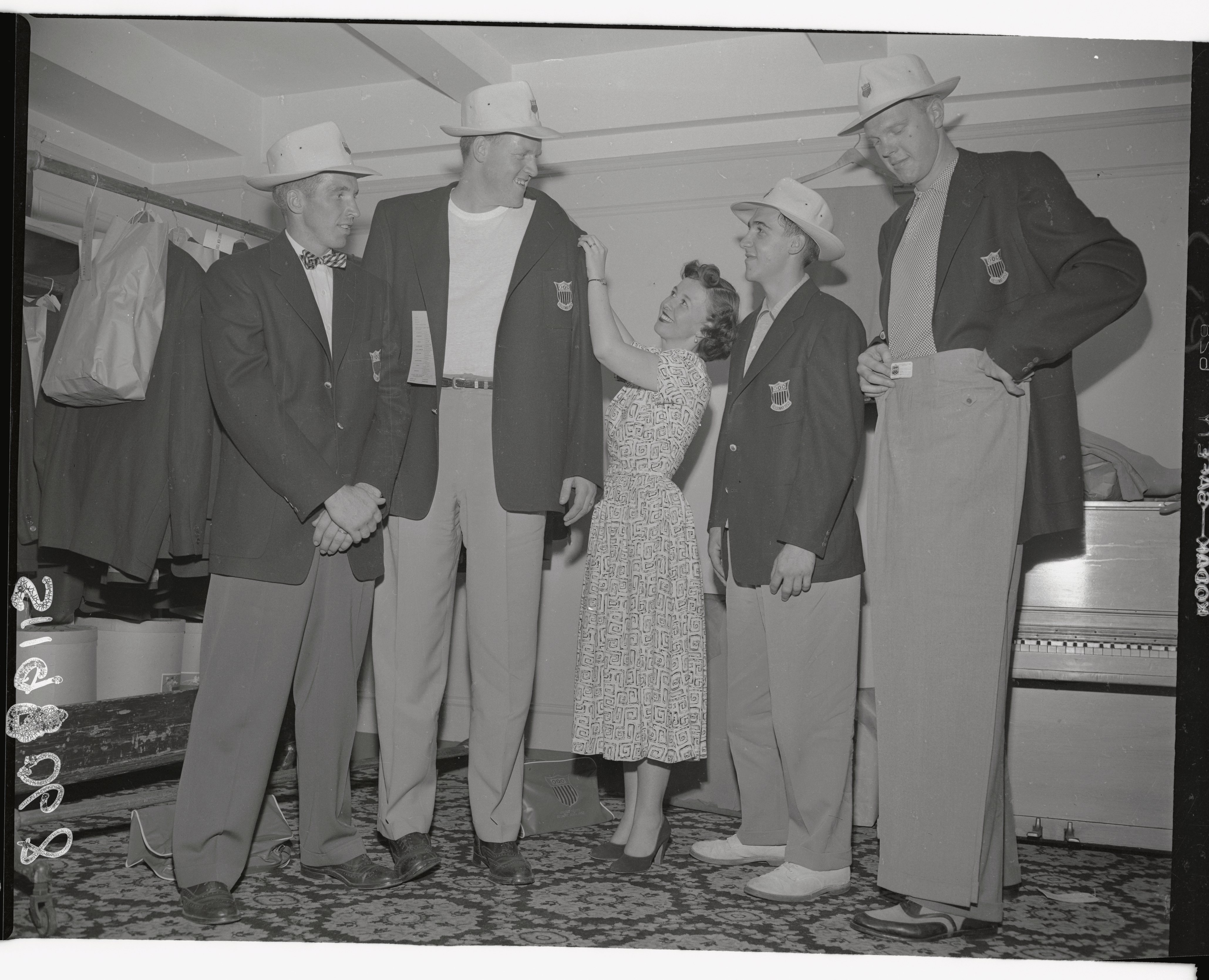 Eleanor McCoy è sminuita dagli atleti (da sinistra) Howard William, Clyde Lovelette, entrambi di Peoria, Illinois; Clyde Dean Kelly di Lawrence, Kansas, e Bob Kurland di Bartsville, Oklahoma, mentre controlla per assicurarsi che le loro giacche olimpiche si adattino nel 1952.