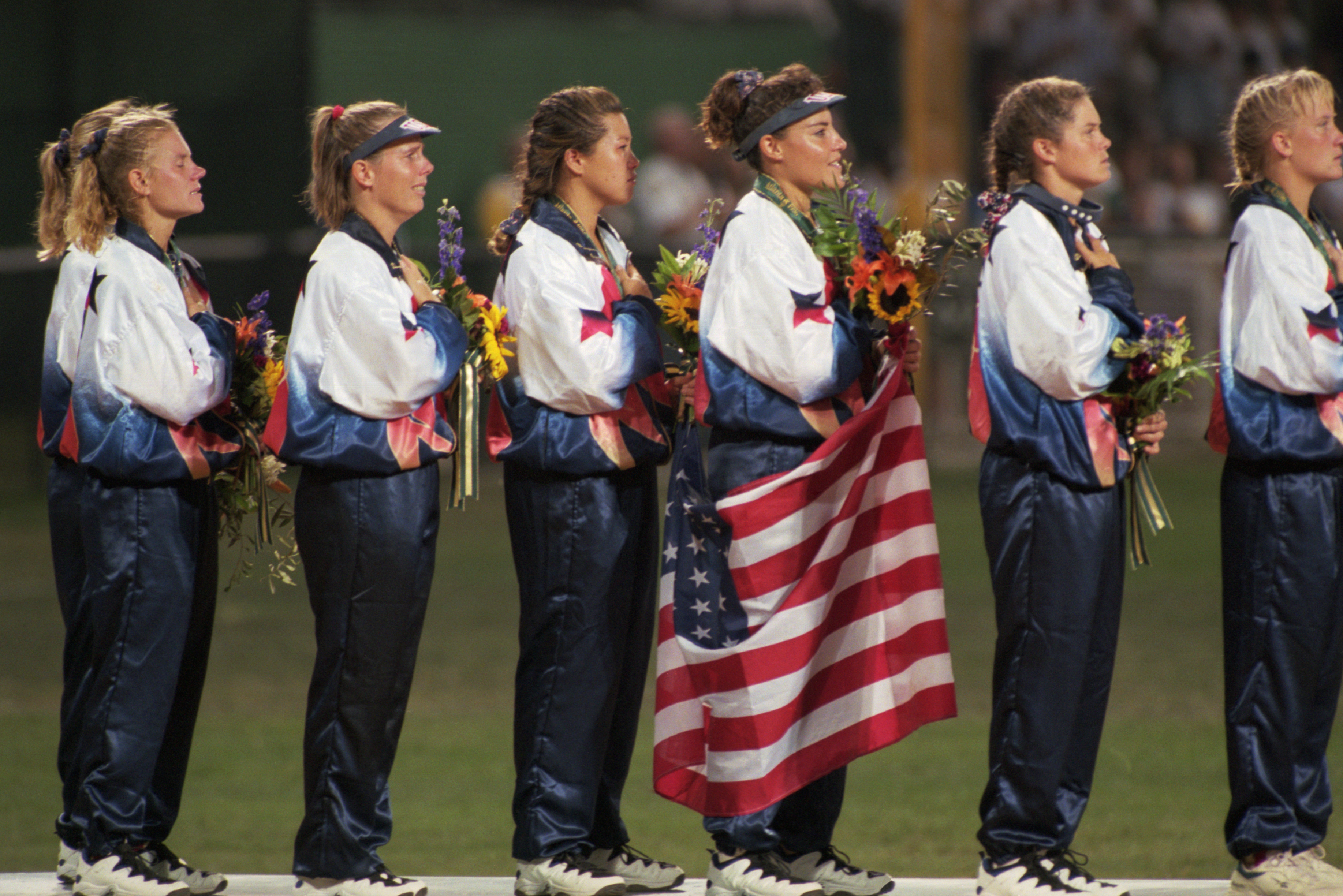 a equipe feminina de softball dos EUA acena para a multidão depois de receber a medalha de ouro nos Jogos Olímpicos de Atlanta de 1996.