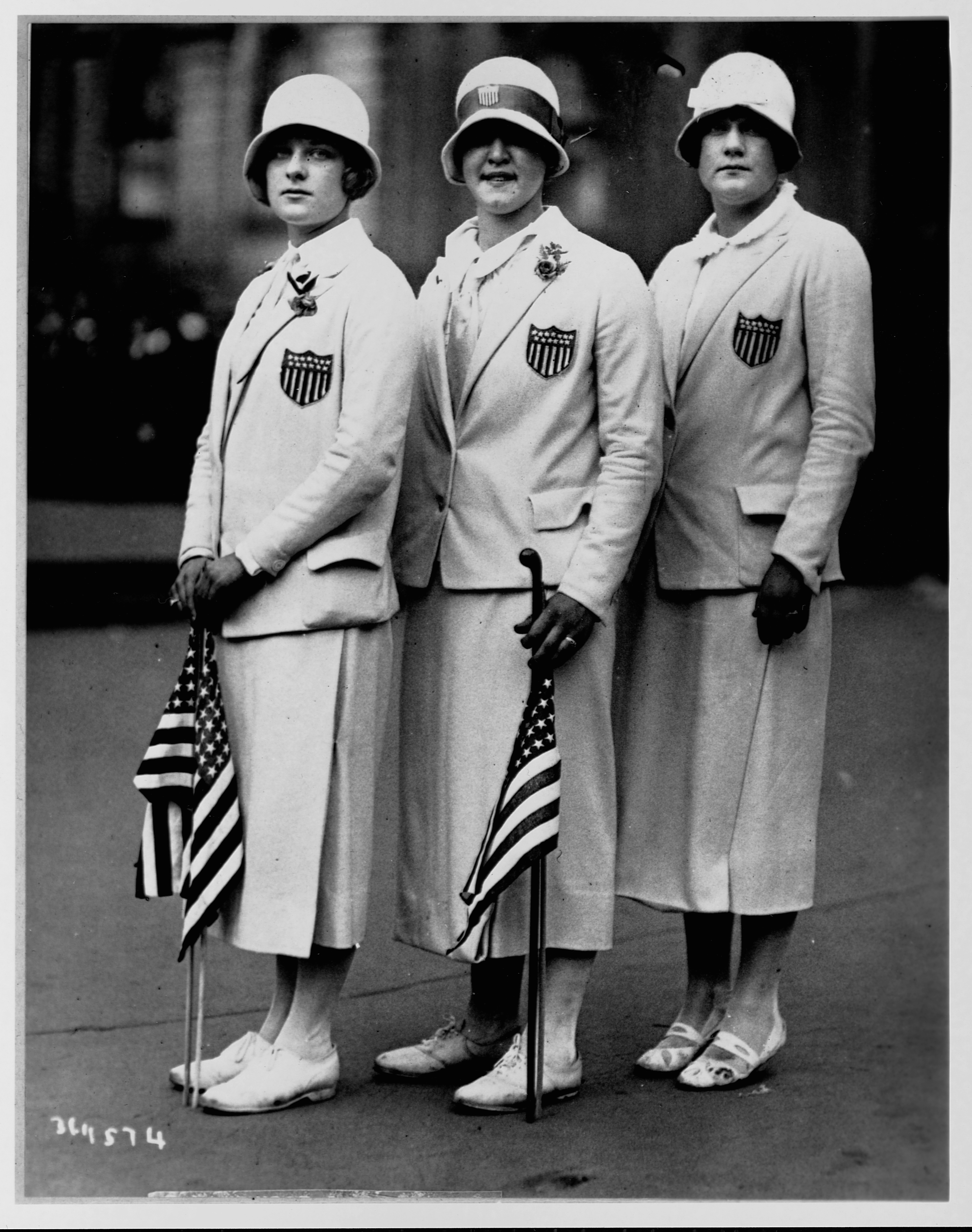  Aileen Riggin, Gertrude Ederle et Helen Wainright portent l'uniforme de leur équipe olympique et brandissent des drapeaux américains, après leur retour des Jeux olympiques de 1920 à Anvers, en Belgique.