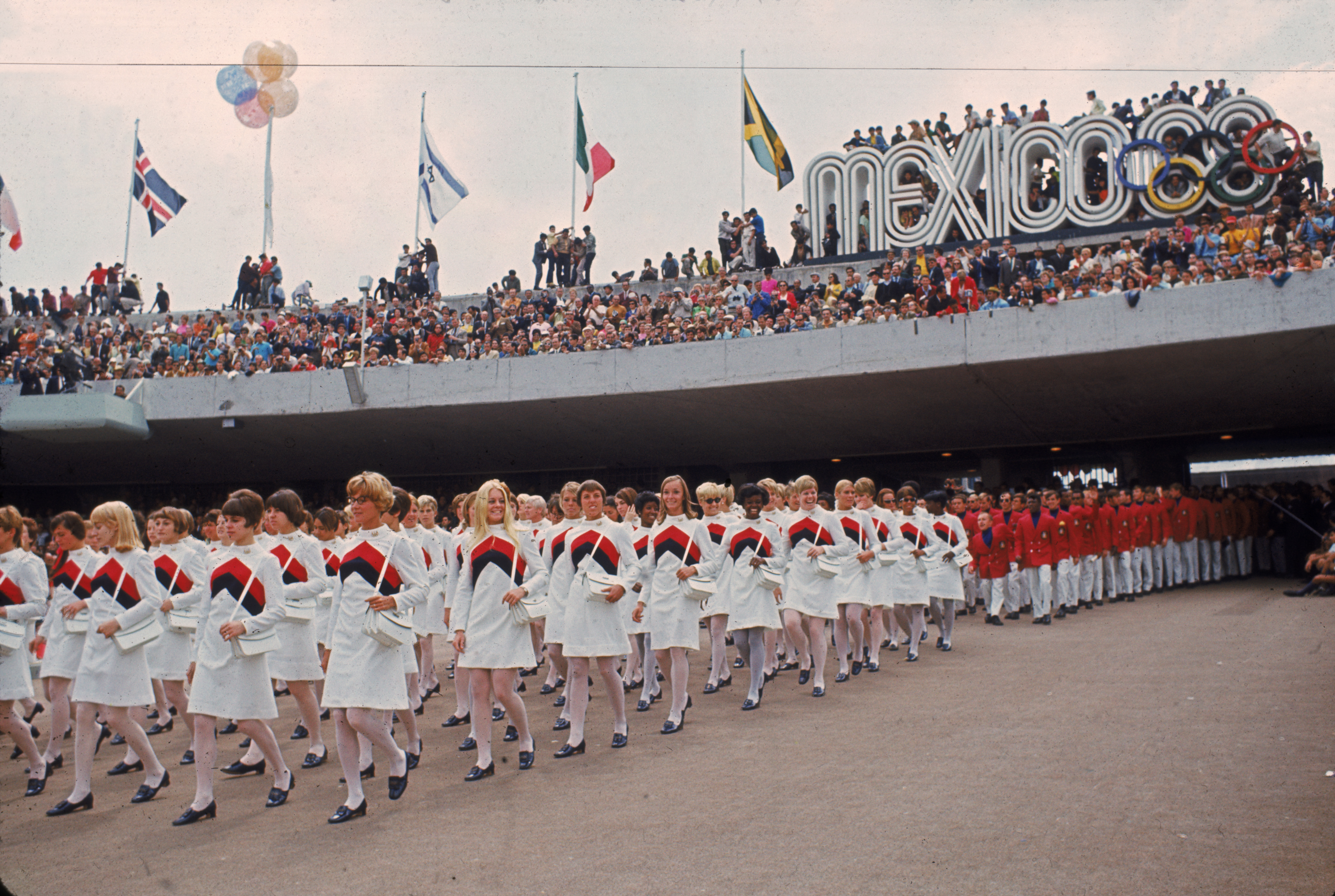 Le donne della squadra olimpica degli Stati Uniti portano le loro controparti maschili nello Stadio olimpico della Città universitaria durante le cerimonie di apertura dei Giochi Olimpici a Città del Messico il Ott. 12, 1968.