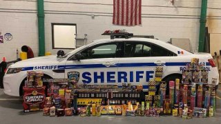 Thousands of dollars in contraband fireworks sit next to a sheriff's vehicle.