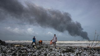 Impoverished Sri Lankans salvage wreckage washed off to the shore from the burning Singaporean ship MV X-Press Pearl which is anchored off Colombo port at Kapungoda, outskirts of Colombo, Sri Lanka, Wednesday, May 26, 2021. A fire on the container ship carrying chemicals raged off Sri Lanka for a sixth day Wednesday and India sent vessels to help douse the blaze, officials said.