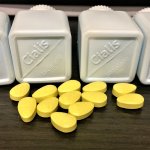 Neon green pills sit scattered on a table, in front of four plastic bottles that read "Cialis." The pills are counterfeits seized by U.S. Customs and Border Protection.