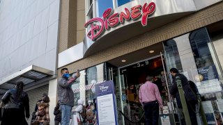 Pedestrians wearing protective masks wait to enter a Disney store in San Francisco, California, on Wednesday, Dec. 23, 2020.