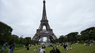 People relax at the Champ-de-Mars garden next to the Eiffel Tower