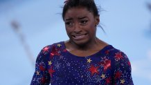 Simone Biles, of the United States, reacts after performing on the uneven bars during the women's artistic gymnastic qualifications at the 2020 Summer Olympics, Sunday, July 25, 2021, in Tokyo.