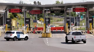 In this photo taken Sunday, May 17, 2020, a truck from Canada heads to the single open lane heading into the U.S. at the Peace Arch border crossing in Blaine, Wash. Canada and the U.S. have agreed to extend their agreement to keep the border closed to non-essential travel to June 21 during the coronavirus pandemic. The restrictions were announced on March 18, were extended in April and now extended by another 30 days. (AP Photo/Elaine Thompson)