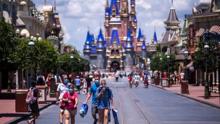 FILE - Guests on Main Street, U.S.A. in front of Cinderella Castle at Walt Disney World Resort's Magic Kingdom on Aug. 9, 2020, in Lake Buena Vista, Fla.
