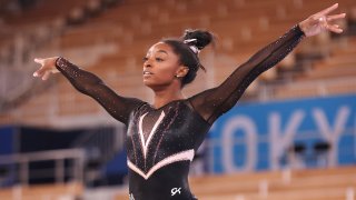 Simone Biles stands with her arms raised.