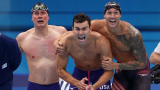 Bowe Becker, Blake Pieroni, Caeleb Dressel and Zach Apple of the United States react after competing in the men's 4 x 100m freestyle relay final on day three of the Tokyo Olympic Games
